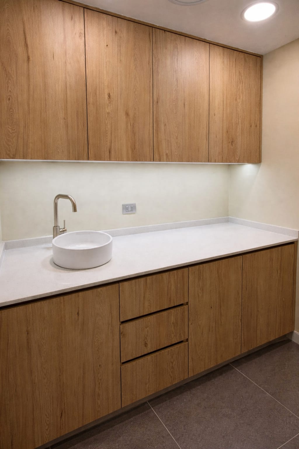Sala clínica com bancada planejada, cuba branca e torneira dourada