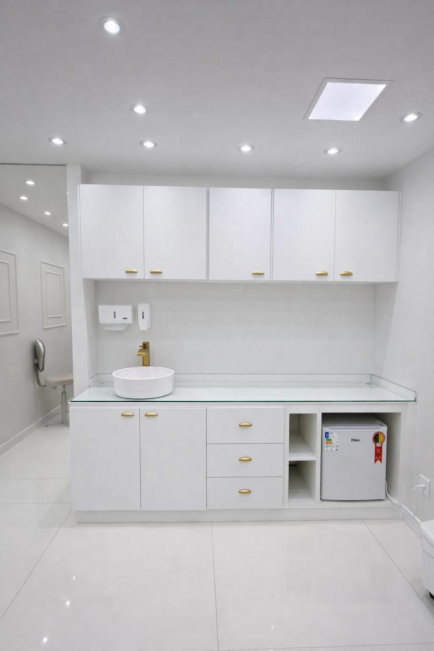 Sala clínica branca com armários planejados e detalhes dourados